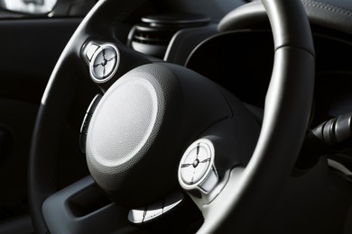 Black steering wheel inside of modern car, closeup