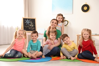 Photo of Kindergarten teacher with group of children in playroom. Indoor activity