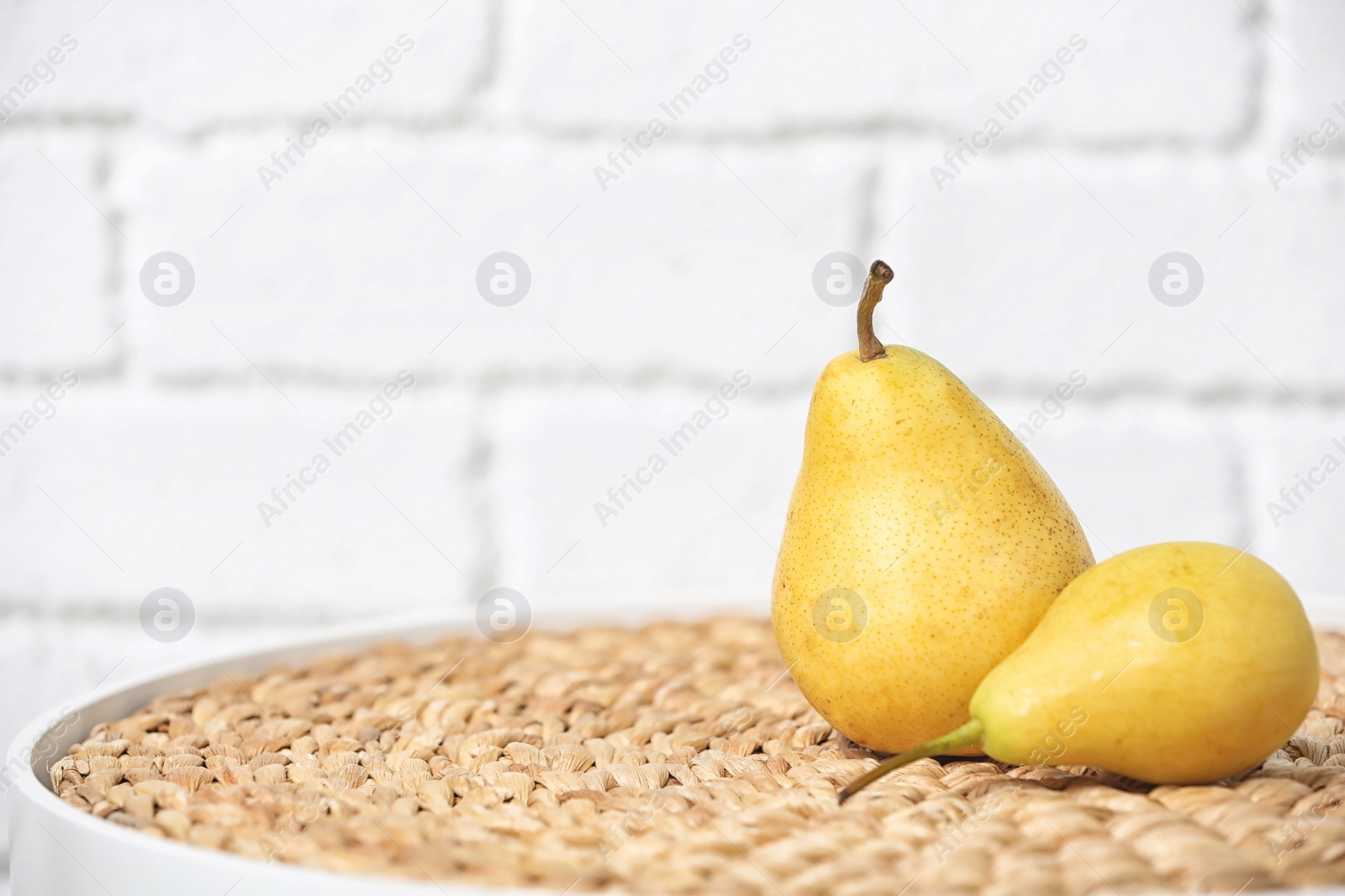 Photo of Ripe pears on table near brick wall. Space for text