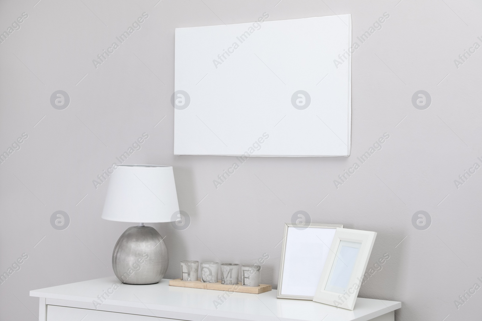 Photo of Blank canvas on wall over console table with decor indoors. Space for design