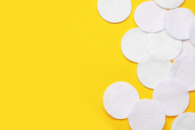 Photo of Soft clean cotton pads on yellow background, flat lay. Space for text