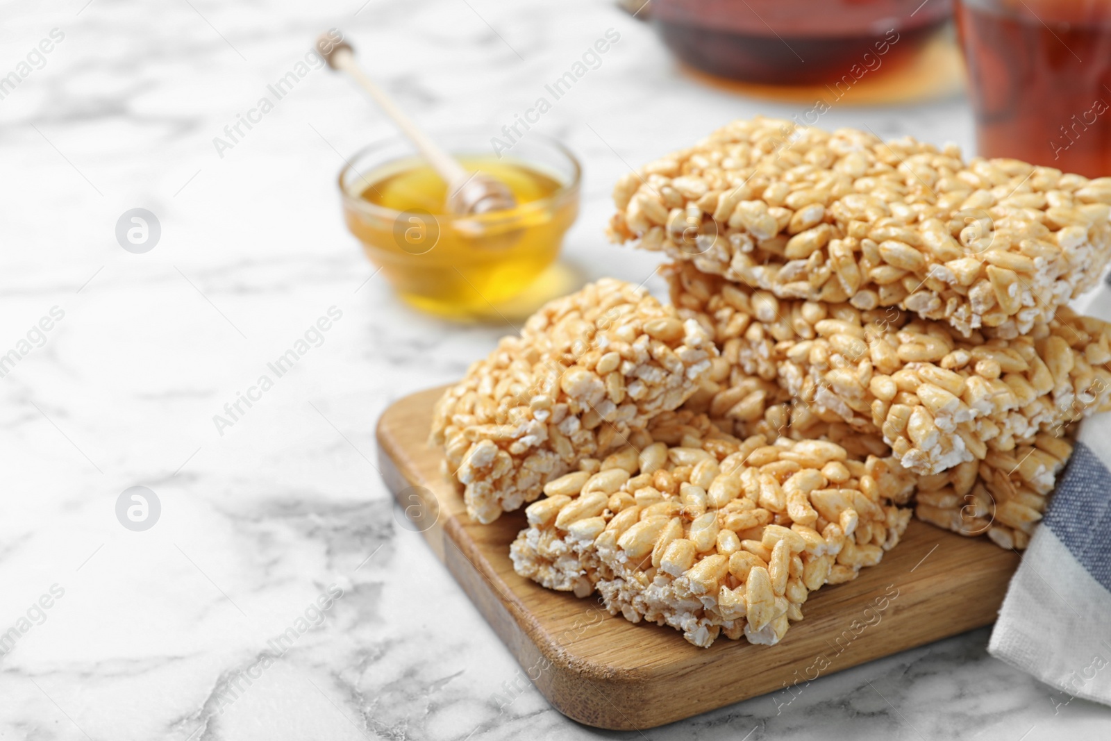 Photo of Delicious rice crispy treats on white marble table, closeup. Space for text