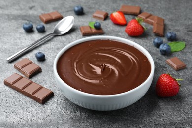 Photo of Delicious chocolate cream with berries and mint on grey table