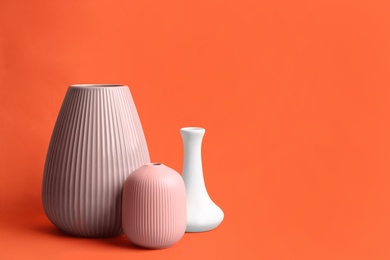 Stylish empty ceramic vases on orange background, space for text