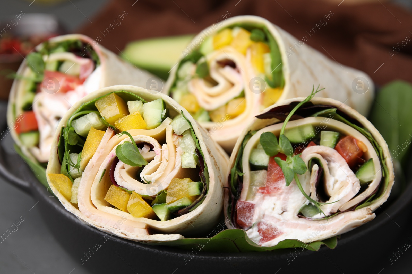 Photo of Delicious sandwich wraps with fresh vegetables on grey table, closeup