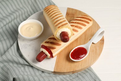 Photo of Delicious french hot dogs and dip sauces on white wooden table