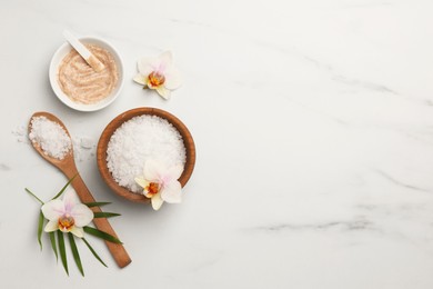 Flat lay composition with different spa products and flowers on white marble table. Space for text