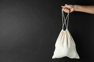 Photo of Woman holding full cotton eco bag on black background, closeup. Space for text