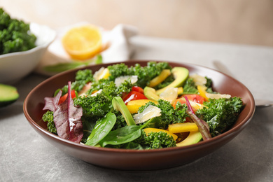 Tasty fresh kale salad on light grey table, closeup