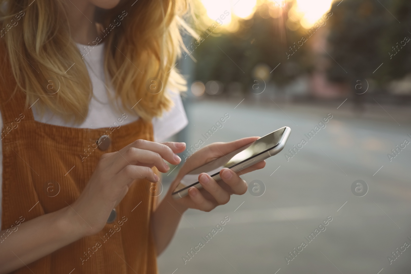 Photo of Woman ordering taxi with smartphone on city street, closeup