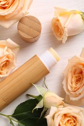 Photo of Lip balm and rose flowers on white wooden background, flat lay