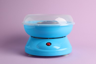 Portable candy cotton machine on violet background