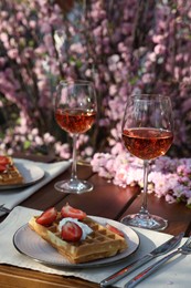 Delicious Belgian waffles with fresh strawberries and wine served on table in garden