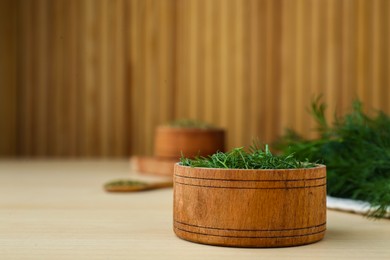 Photo of Bowl of fresh dill on wooden table, space for text