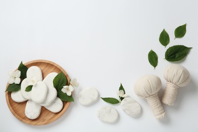 Photo of Spa stones, beautiful jasmine flowers and herbal bags on white background, flat lay. Space for text