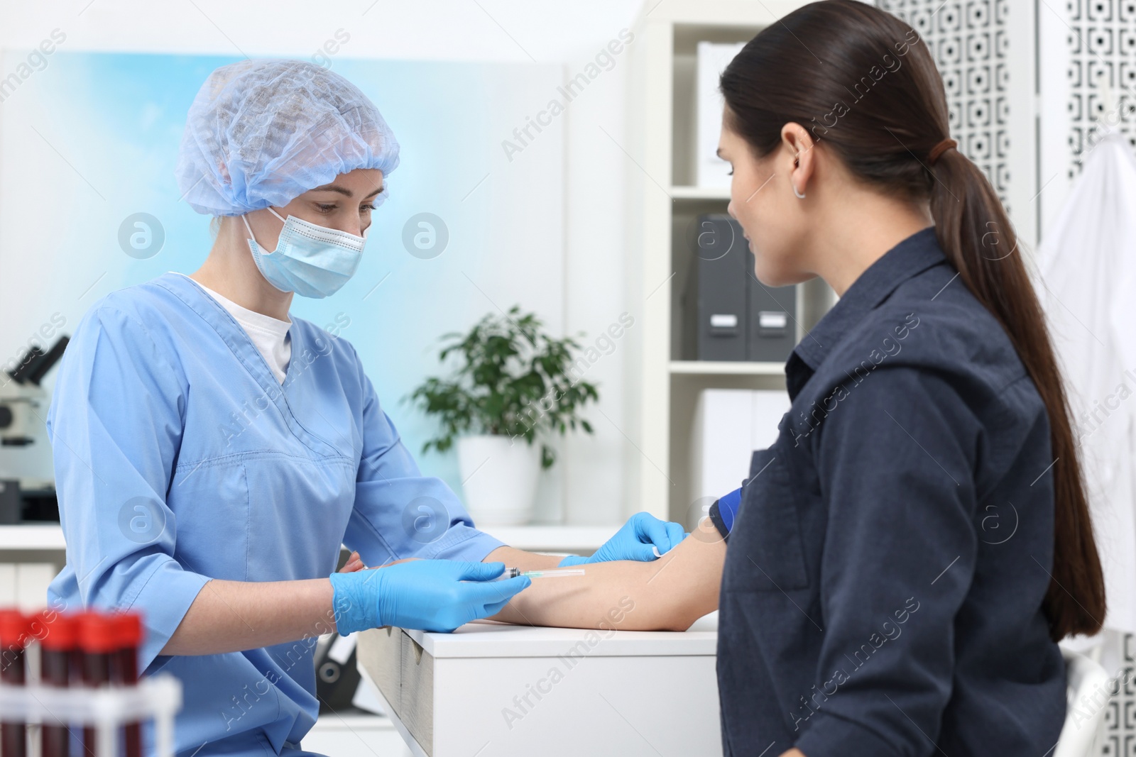 Photo of Laboratory testing. Doctor taking blood sample from patient at white table in hospital