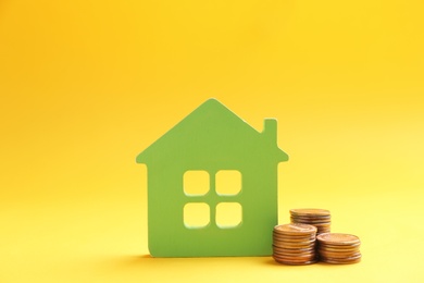 House figure and coins on color background