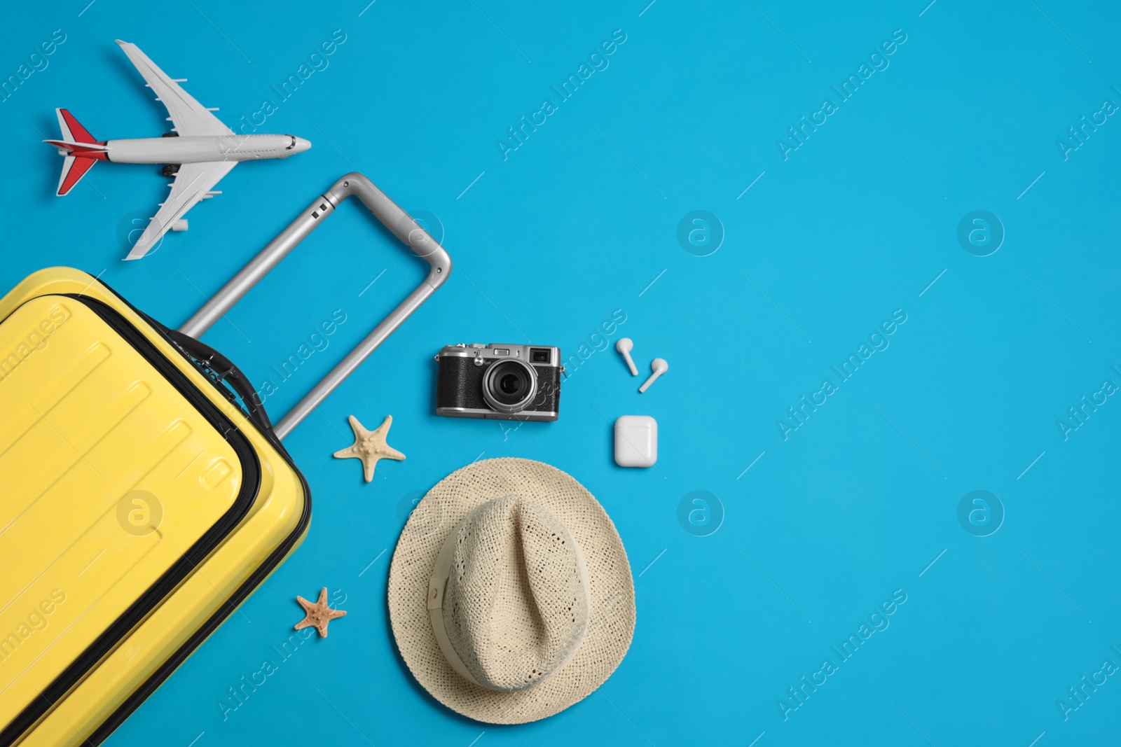 Photo of Flat lay composition with suitcase and travel accessories on light blue background, space for text. Summer vacation