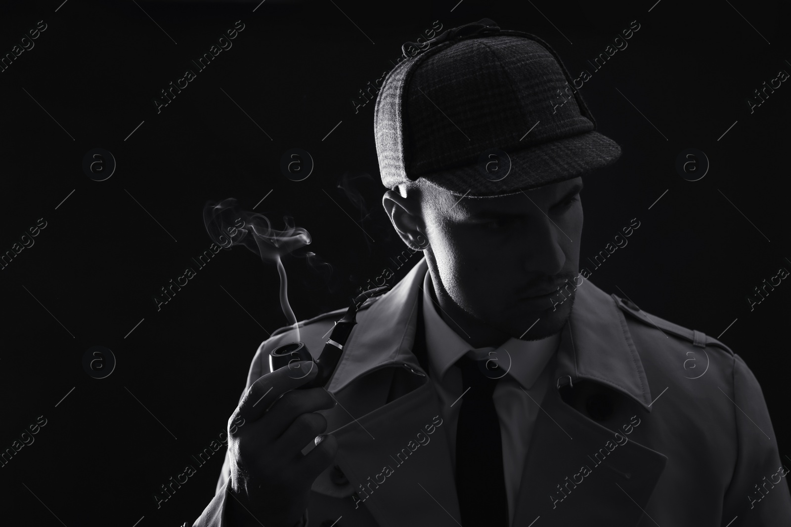 Photo of Old fashioned detective smoking pipe on dark background, black and white effect