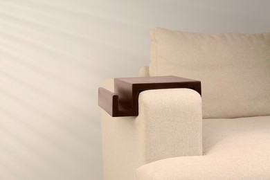 Wooden armrest table on sofa indoors, space for text. Interior element