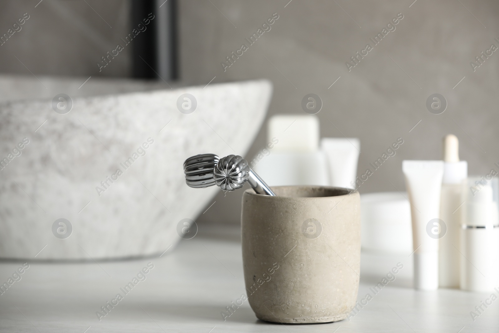 Photo of Holder with metal face roller on counter in bathroom