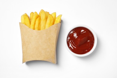 Paper cup with French fries and ketchup on white table, flat lay