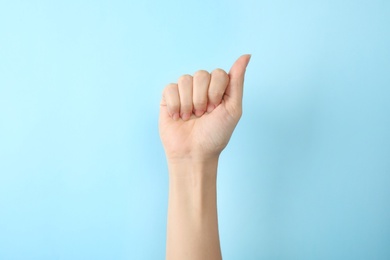 Woman showing A letter on color background, closeup. Sign language