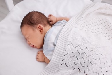 Photo of Cute newborn baby sleeping under white plaid on bed