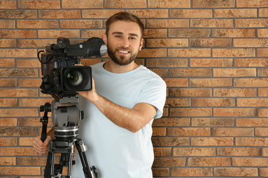 Photo of Operator with professional video camera near brick wall
