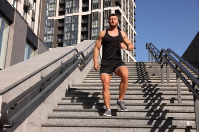 Photo of Man running down stairs outdoors on sunny day, low angle view