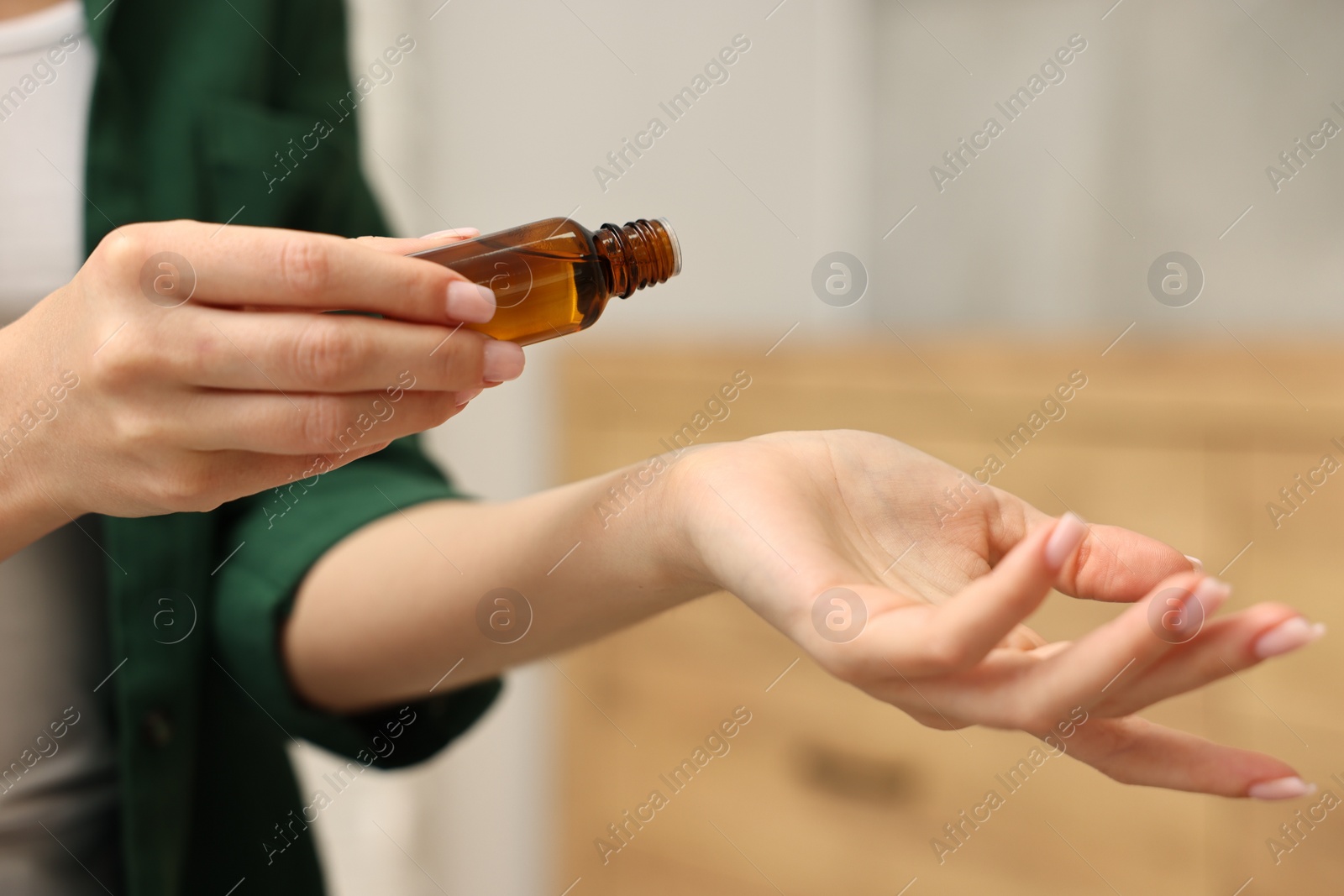 Photo of Aromatherapy. Woman with bottle of essential oil against blurred background, closeup