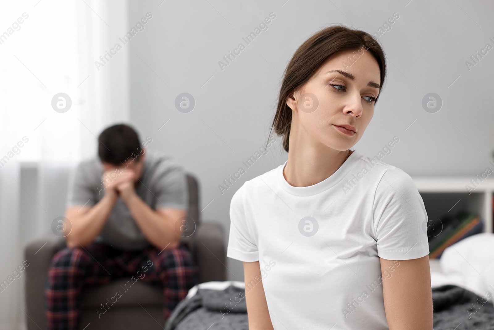 Photo of Offended couple ignoring each other after quarrel in bedroom, selective focus. Relationship problems