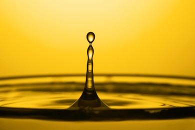 Image of Splash of golden oily liquid on yellow background, closeup