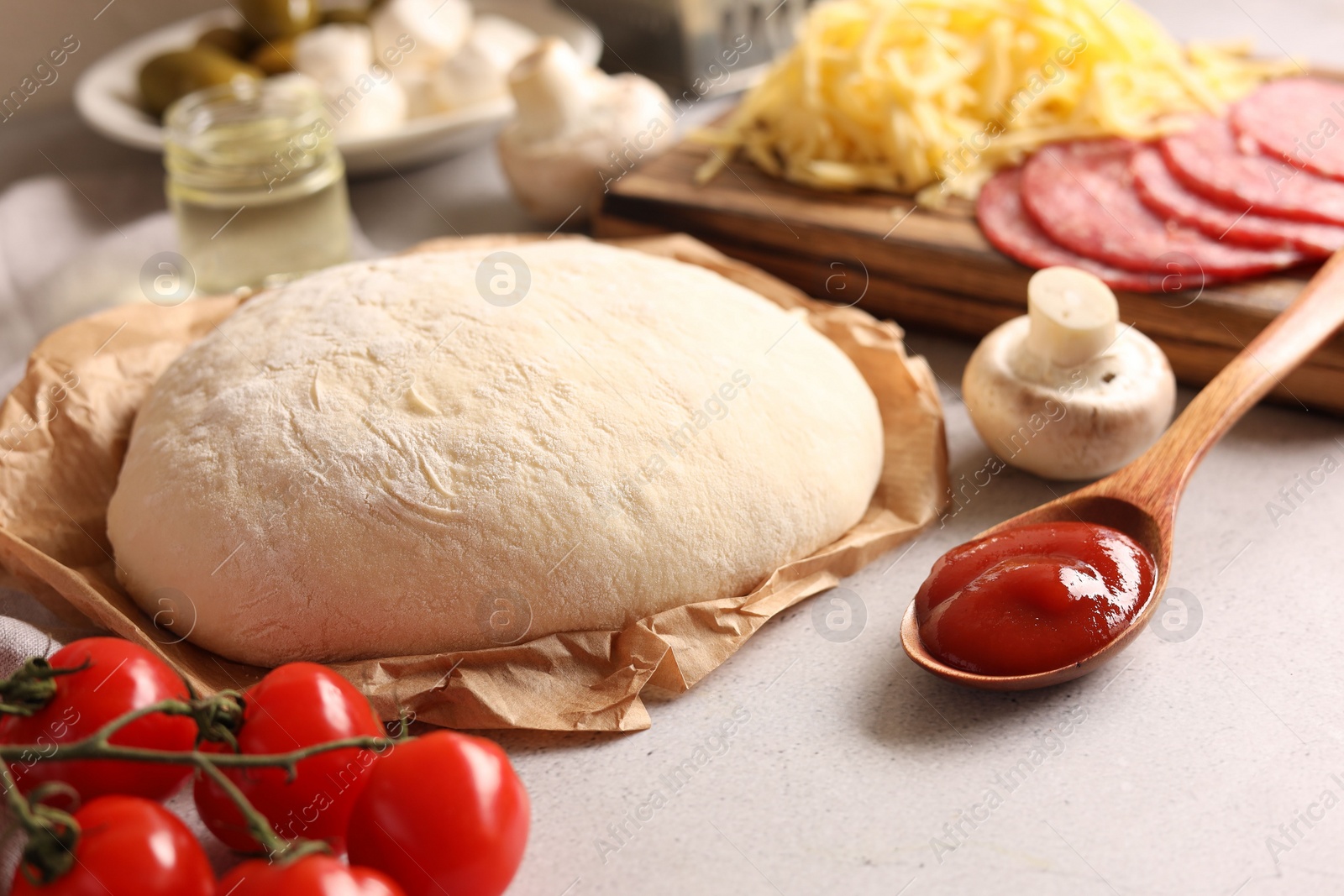 Photo of Pizza dough and products on gray textured table, closeup