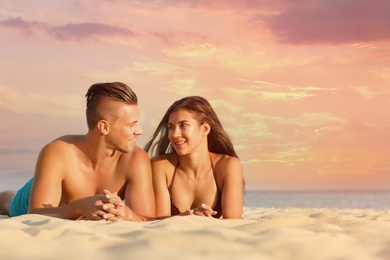 Photo of Young woman in bikini spending time with her boyfriend on beach. Lovely couple