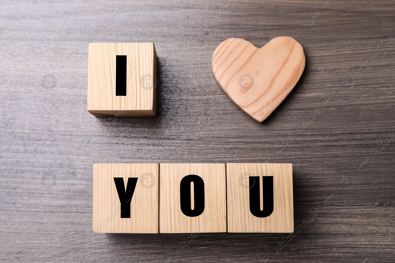 Photo of Phrase I love You made of decorative heart and cubes on wooden background, flat lay