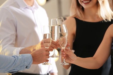 Photo of Friends clinking glasses with champagne at party indoors, closeup