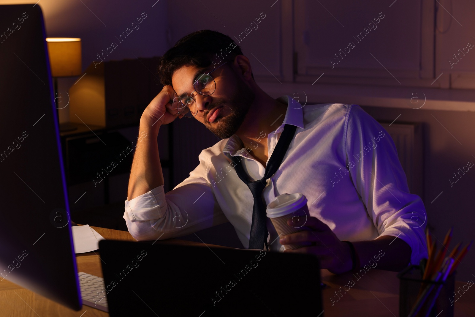 Photo of Tired man with coffee working late in office