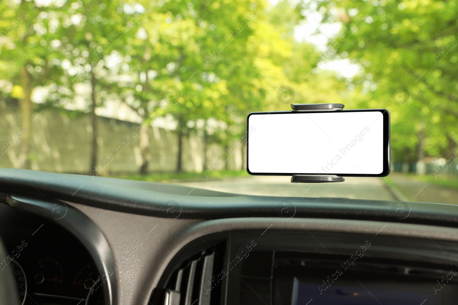 Photo of Car holder with modern mobile phone on windshield of automobile. Mockup for design