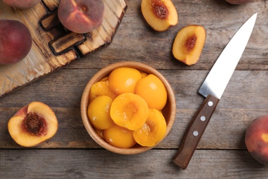 Flat lay composition with canned and fresh peaches on wooden background