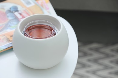 Photo of Wax air freshener and magazines on white table indoors, space for text. Interior elements