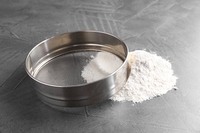 Metal sieve and flour on grey table