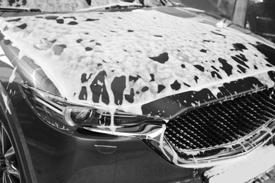Photo of Luxury automobile covered with foam at car wash, closeup