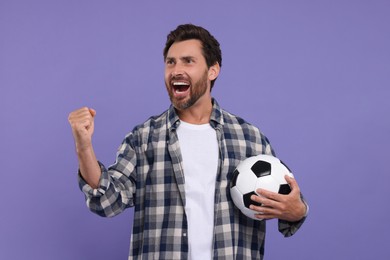 Emotional sports fan with soccer ball on purple background
