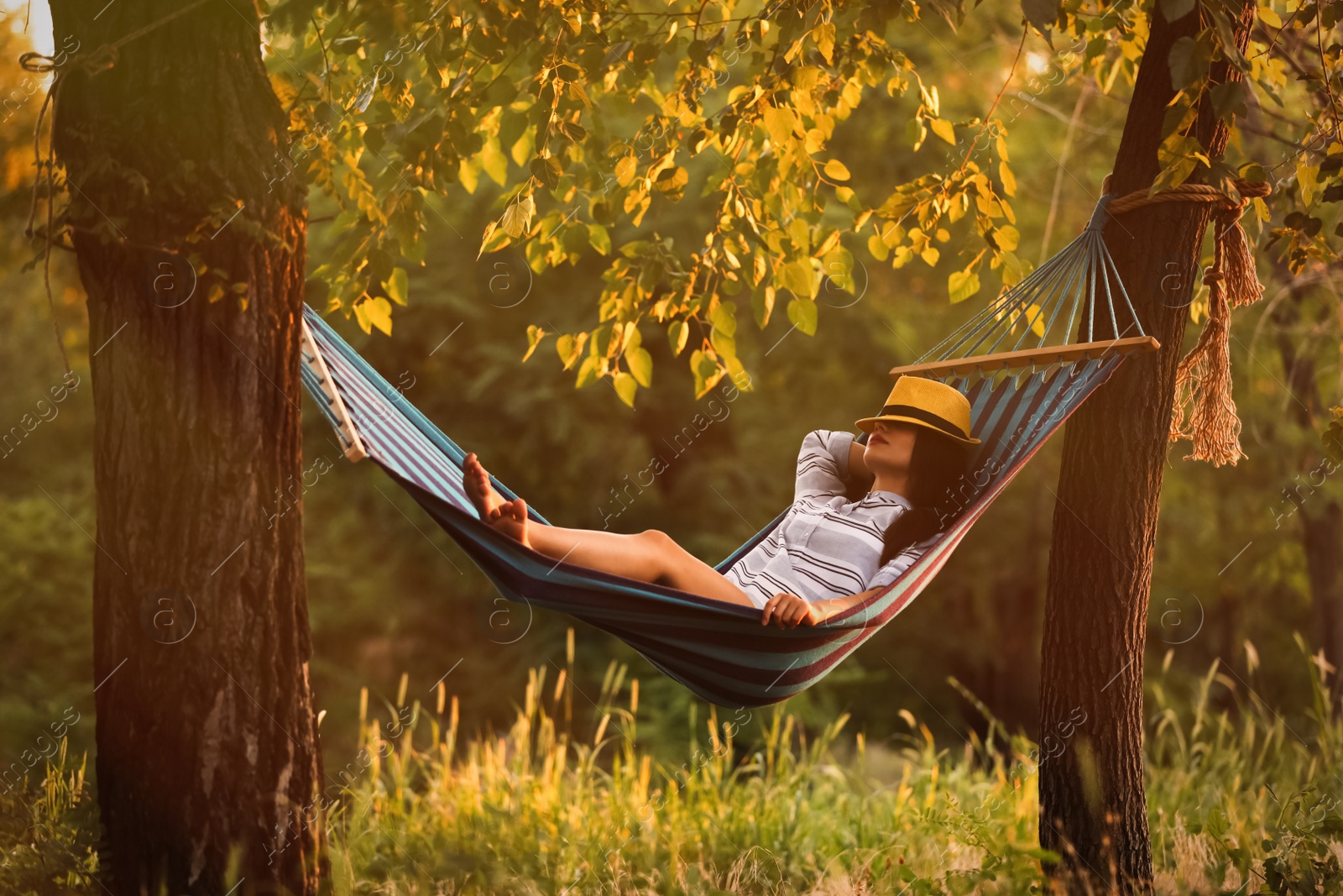 Photo of Young woman resting in comfortable hammock at green garden