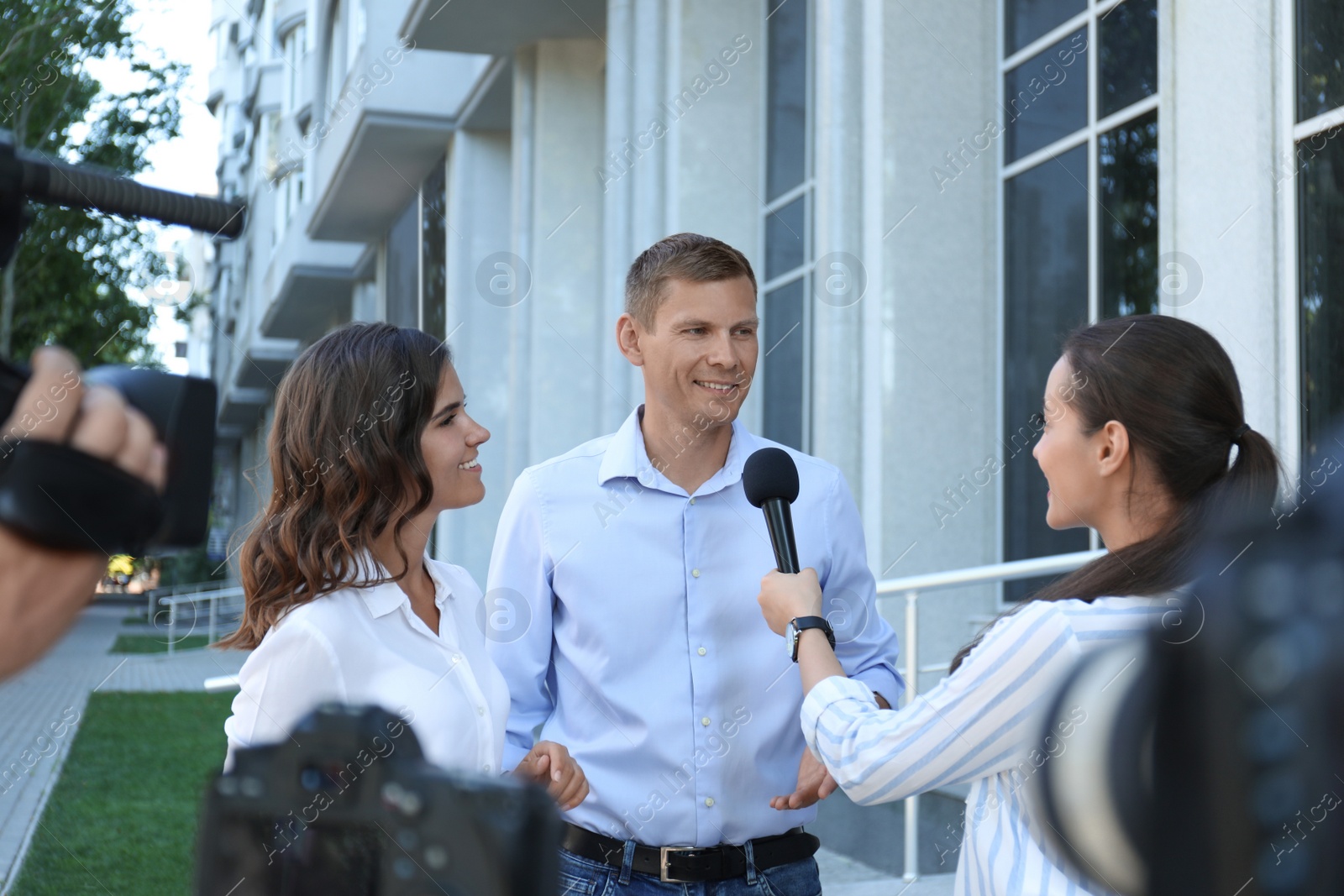 Photo of Professional journalist and operator with video camera taking interview outdoors