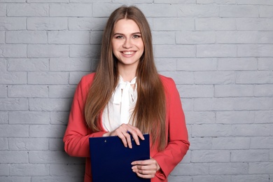 Photo of Beautiful real estate agent with clipboard on brick wall background