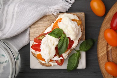 Photo of Delicious sandwich with burrata cheese and tomatoes served on grey wooden table, flat lay