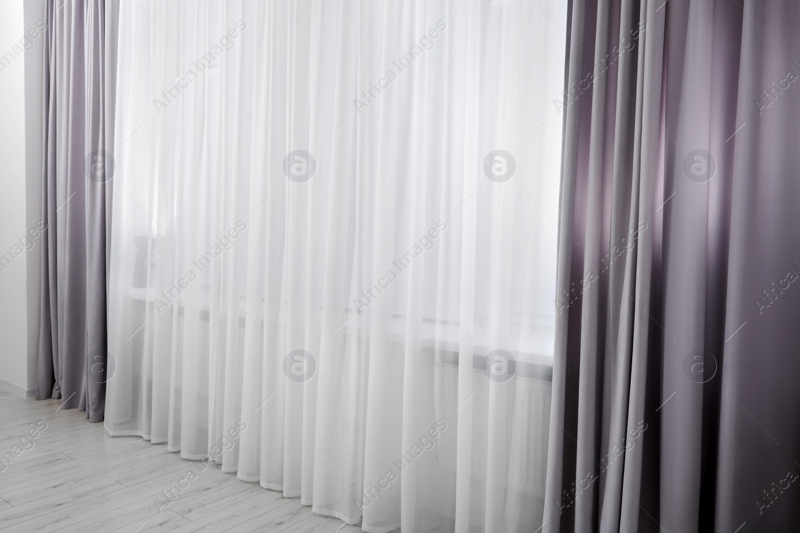 Photo of Light grey window curtains and white tulle indoors