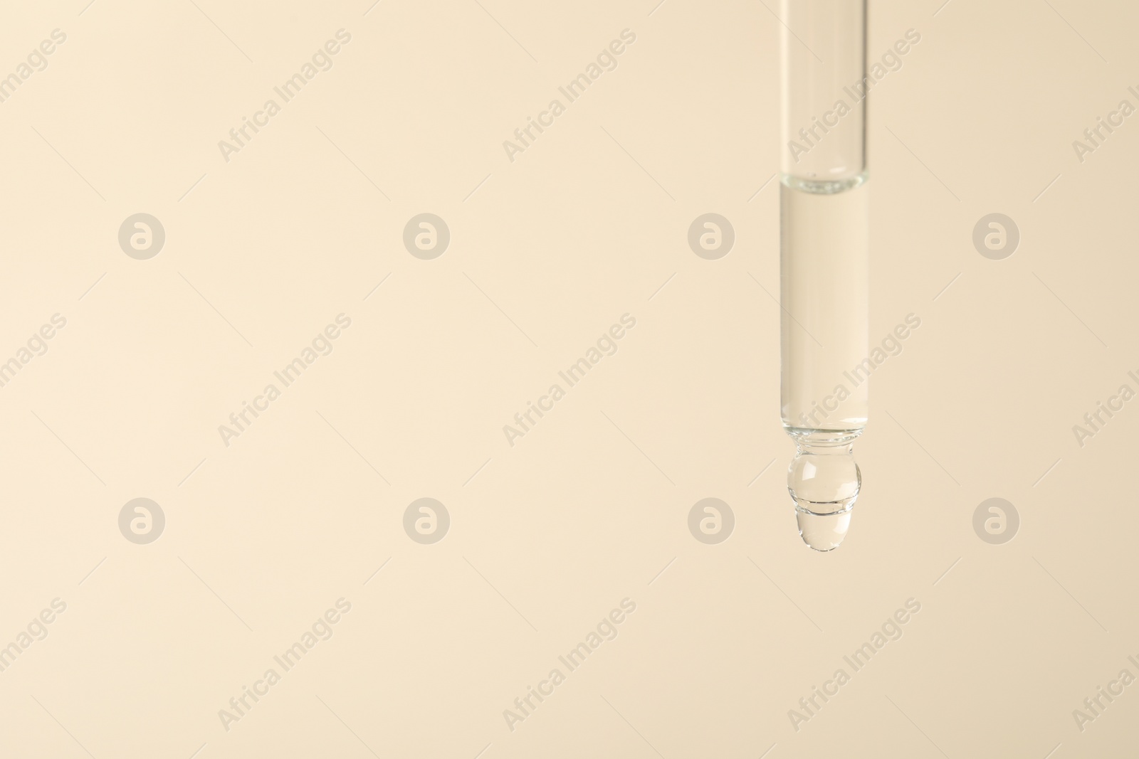 Photo of Dripping cosmetic serum from pipette on beige background, space for text